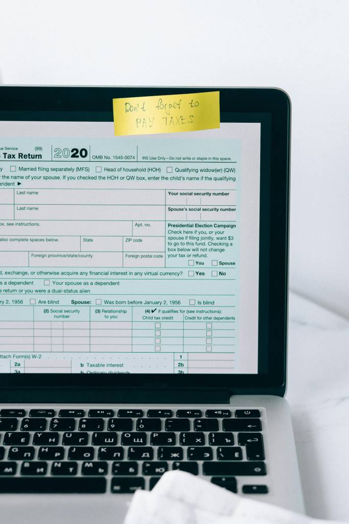 Tax Return Document file on a computer with a sticky note reminder.